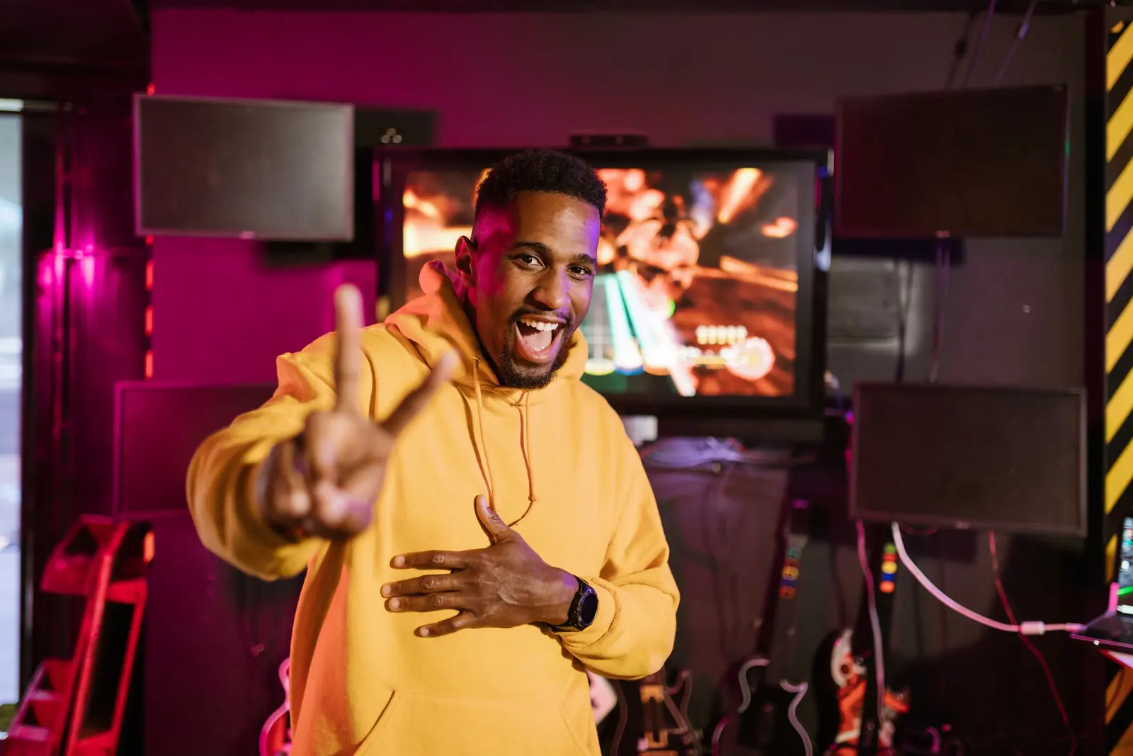 A smiling gamer in a yellow hoodie pointing straight at the camera